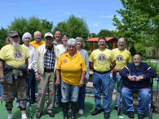Group of visitors standing on a landscaped outdoor miniature golf course at Brookside Miniature Golf in Branson, Missouri