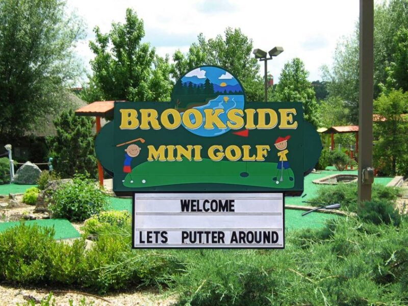 Brookside Mini Golf welcome sign at the outdoor mini golf entrance with landscaped putting greens and greenery in Branson, Missouri